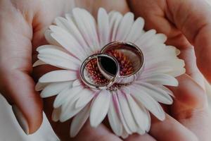 Silver wedding rings against flower on womans hands. Close up shot. Marriage symbol. Jewelry. Love and romance concept. photo