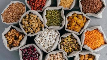 Various grains and dried fruit in hessian bags on market stall. Top view. Set of organic healthy products. Healthy eating concept photo