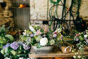 Variety of flowers in wooden backets. Bouquetes standing on wooden table. Composition with flowers with pleasant smell. Decoration concept. Flower shop with beautiful flowers photo