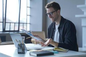 Young German businessman in glasses discussing calculation chart reports with partners online photo