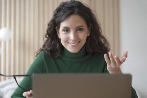 una joven italiana sonriente profesora tutora habla con los estudiantes durante la lección en línea en una laptop foto