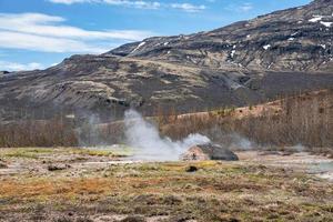 Scenic view of geothermal smoking field at Smidur Geyser valley against mountain photo