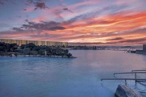 View of geothermal spa in blue lagoon against cloudy sky during sunset photo