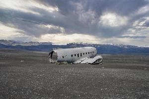 Broken airplane wreck at famous black beach in Solheimasandur against cloudy sky photo