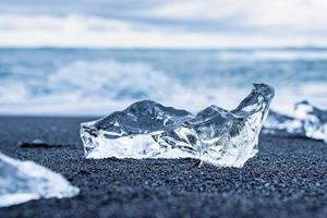 primer plano de un trozo de hielo brillante en la orilla de arena negra de la playa de diamantes