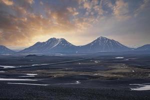 Idyllic view of snow on volcanic landscape against mountains during sunset photo