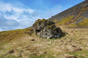 Close-up of rock formation on grassy landscape of mountain against blue sky photo