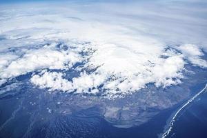 Aerial view of beautiful snowy white landscape and ocean covered with cloudscape photo