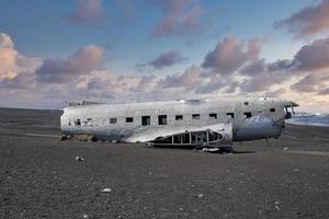 accidente de avión dañado abandonado en la playa de arena negra en solheimasandur al atardecer foto