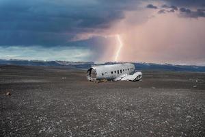 Lightning over broken airplane wreck at black sand beach in Solheimasandur photo
