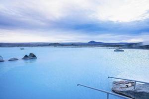 Scenic view of blue lagoon in geothermal spa against cloudy sky in valley photo