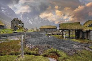 Tiretracks by traditional houses in Viking village against cloudy sky at sunset photo