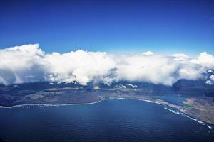 Beautiful cloudscape covering scenic landscape and ocean against blue sky photo