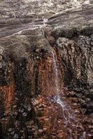 hermosa vista de una pequeña cascada cayendo sobre columnas de roca basáltica de la montaña foto