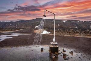 estación de ducha caliente de la energía geotérmica en krafla contra la montaña durante la puesta de sol foto