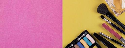 Makeup cosmetics on pink-yellow background. Top view. Banner. Copy space photo