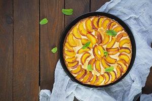 Delicious homemade peach pie on wooden background. Top view photo