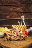 Club sandwich with ham, cheese, tomato, salad and chips photo