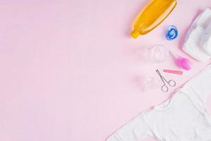 Baby clothes and other stuff for child on pink background. Newborn baby concept. Top view photo