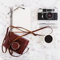 Flat lay, top view office table desk. Desk workspace with retro camera, diary, pen, glasses, case, cup of coffee on white background. photo