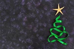 Christmas tree made of ribbon and starfish on dark background. Top view photo