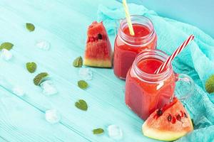 delicioso batido de sandía fresco con hielo sobre fondo azul foto