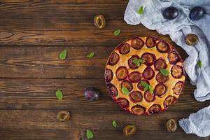 Delicious homemade plum pie on rustic background. Top view photo