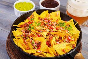 Mexican nachos with cheese. Corn chips with guacamole, salsa and tomato ketchup. photo