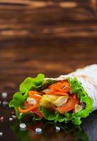 Delicious shawarma sandwich on wooden background photo