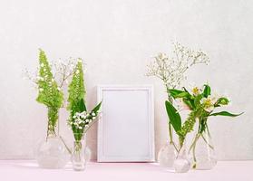 Flowers and plants in flask with frame. Beautiful spring background with flowers in vase. photo