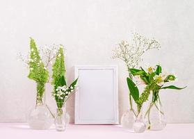 Flowers and plants in flask with frame. Beautiful spring background with flowers in vase. photo