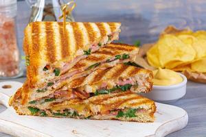 Club sandwich with ham, cheese, tomato, salad and chips photo