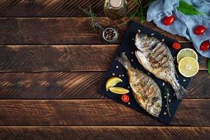 Grilled dorado fish on wooden background. Roasted seafish with spice and herbs photo