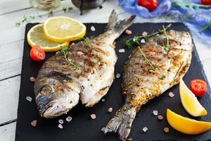 Grilled dorado fish on wooden background. Roasted seafish with spice and herbs photo