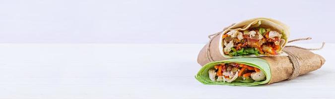 Delicious shawarma sandwich with chicken on wooden background photo