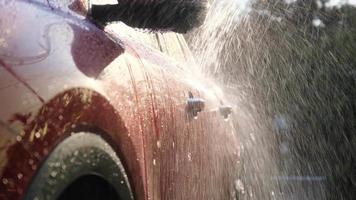 close-up de água fluindo em um carro enquanto um trabalhador está usando uma lavadora de alta pressão para lavar o carro. conceito de serviço de lavagem de carro. video