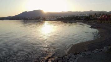 precioso sol de un atardecer reflejandose en un mar en calma en la playa. video