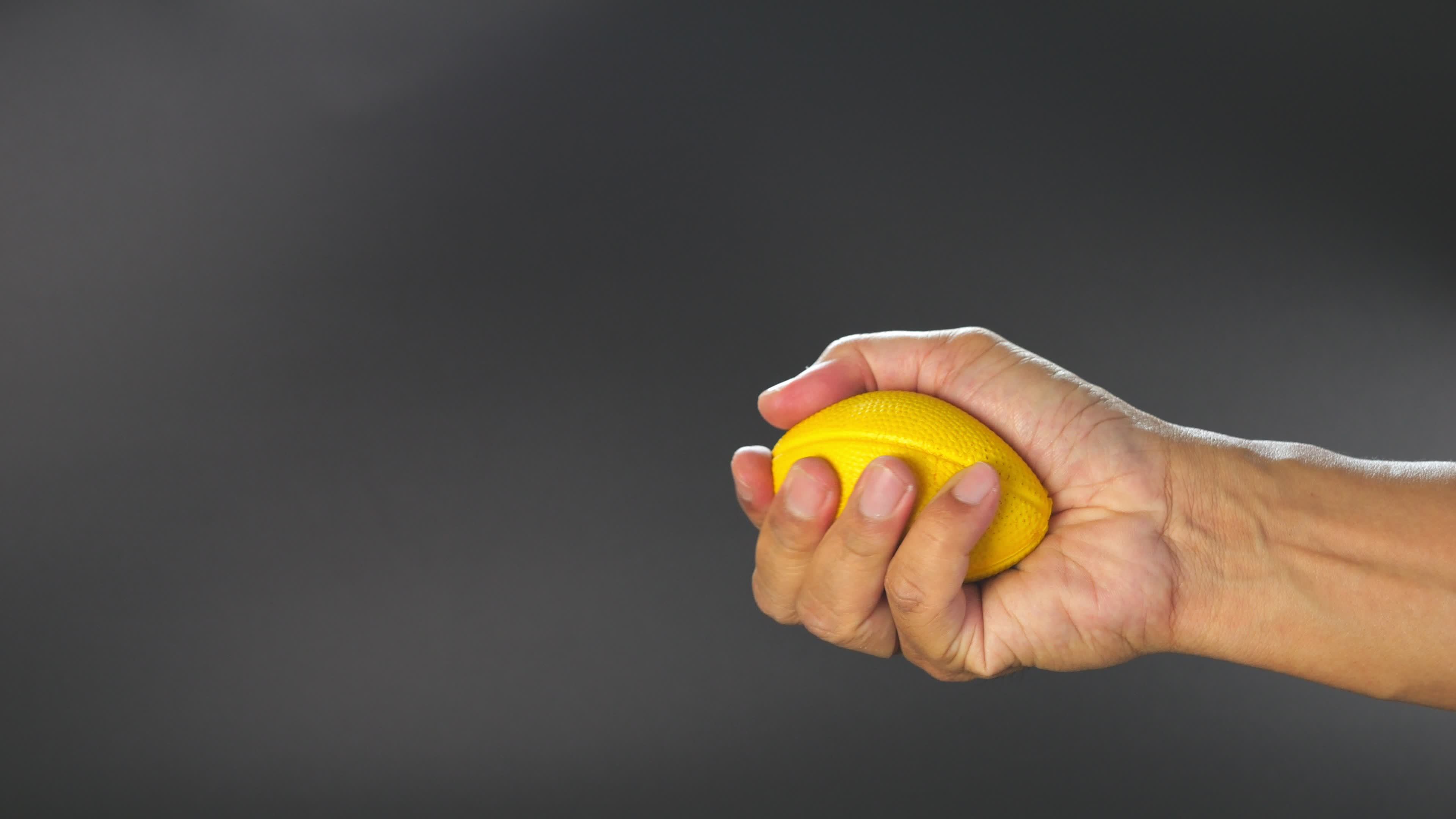 Closeup slow motion hand squeezing yellow simulation ball exercises