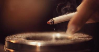 Woman drops ash of a cigarette into the ashtray, beautiful wisp of smoke
