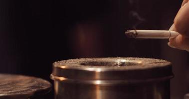 Woman drops ash of a cigarette into the ashtray, beautiful wisp of smoke