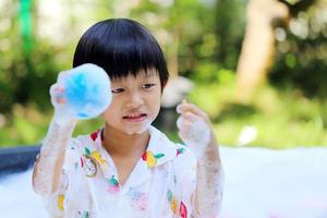 Asian boy playing ball and bubble foam in basin at backyard in sunshine day, Happy boy play splashing water with toy photo