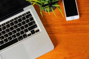 Top view of laptop with smartphone on wooden table. photo