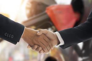 Image of businessman shaking hands after successful oil price negotiation with refueling car blurred in the background, industrial business idea photo