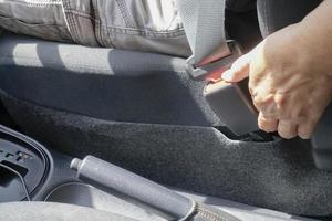 Close up female  unfastens car seat belt with her hand in car. Safety and transport concept photo