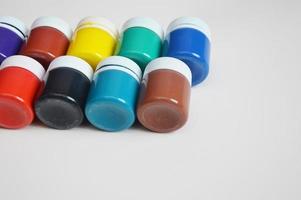 A set of jars of gouache paints. Different colors of bright paints in closed packages on a light background. Free space for text. photo