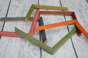 Decorative modern colored picture frames. Patterns of frames for a baguette, lying on a wooden background. Workshop photo