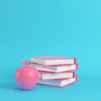 Pink apple and stack of books on bright blue background in pastel colors photo