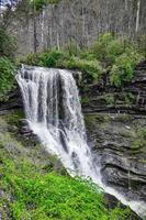 A scenic waterfall roadside going over the cliff down to the boulders and rocks below where you can no longer drive under but can walk underneath the raging waters photo