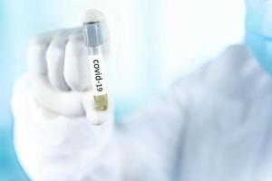 cierre un tubo de ensayo en la mano de un médico del laboratorio científico, un concepto de uso de drogas para tratar y proteger la pandemia global de covid-19 foto