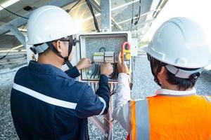 Workers use clamp meter to measure the current of electrical wires produced from solar energy for confirm to normal current photo